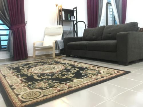 a living room with a black couch and a rug at Arwaa Homestay Beachview in Bachok