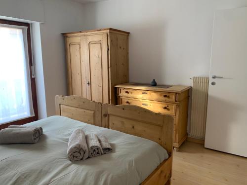 um quarto com uma cama com uma cómoda e 2 toalhas em Appartamento Corte del Tito em Castello di Fiemme