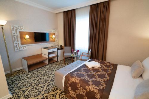 a hotel room with a bed and a television at The Green Park Diyarbakir in Diyarbakır