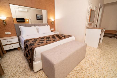 a hotel room with a large bed and a ottoman at The Green Park Diyarbakir in Diyarbakır