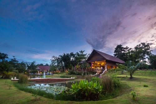 a resort with a pond in front of a building at Sasidara Resort Nan in Nan