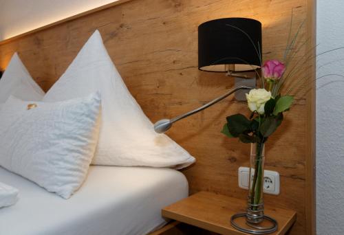 a bed with a lamp and a vase of flowers on a table at Hotel Waldfrieden "Das kleine Hotel" in Spiegelau
