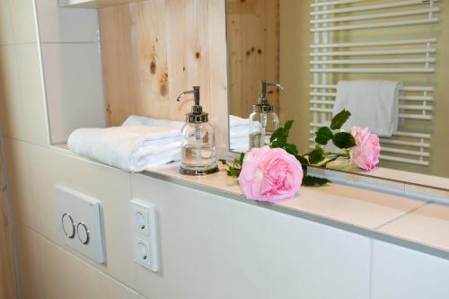 フュルトにあるNatur Apartments Nataliaのバスルーム(鏡、ピンクの花が飾られたカウンター付)