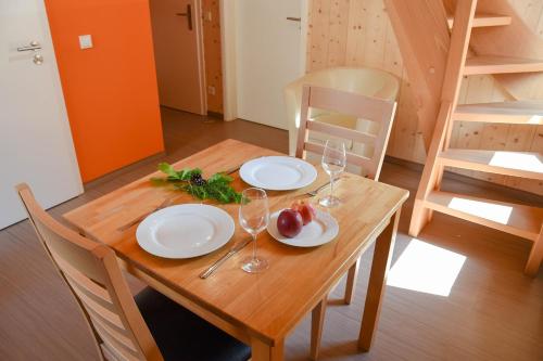 a wooden table with plates and wine glasses on it at Natur Apartments Natalia in Fürth