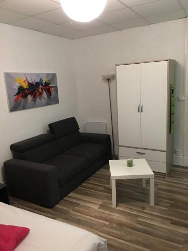 a living room with a black couch and a table at charmand studio dans l ancien hotel le continental in Vittel