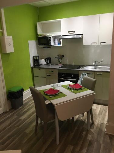 a kitchen with a table and chairs in a kitchen at charmand studio dans l ancien hotel le continental in Vittel