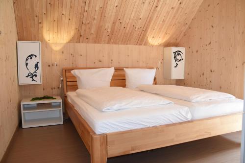 Schlafzimmer mit einem Holzbett mit weißer Bettwäsche in der Unterkunft Natur Apartments Natalia in Fürth