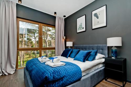 a bedroom with a large bed with blue pillows at BlueApart Verano Residence in Jurata