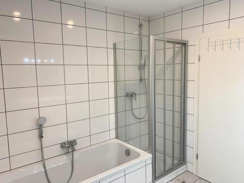 La salle de bains blanche est pourvue d'une douche et d'une baignoire. dans l'établissement My-Skypalace Dirmstein, à Dirmstein