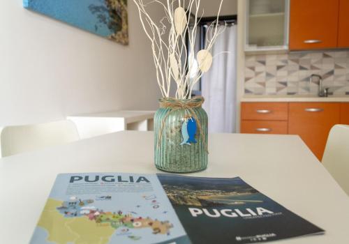 książka siedząca na stole obok wazy z kwiatami w obiekcie Villette Stella Marina - Localo w mieście Torre dell'Orso