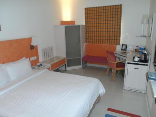 a bedroom with a bed and a desk and a kitchen at Aditya Hometel in Hyderabad