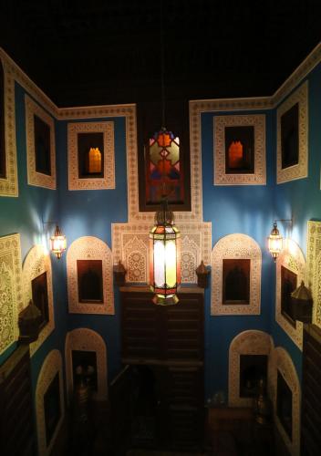 a room with a blue wall with a lamp and pictures at Riad Hiba in Meknès