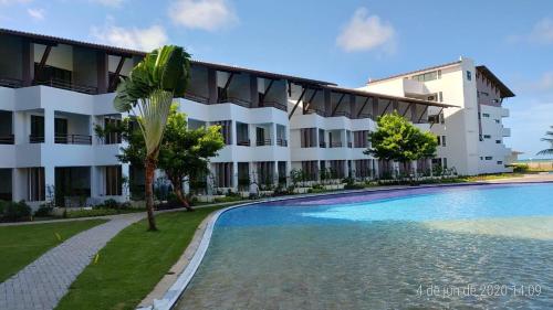 un hotel con piscina frente a un edificio en Maui Beach Residence, en Tamandaré
