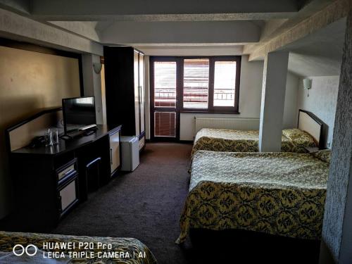 a hotel room with two beds and a television at Ribkata Family Hotel in Smolyan