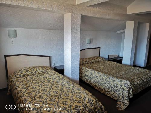 a hotel room with two beds and two lamps at Ribkata Family Hotel in Smolyan