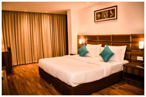 a hotel room with a large bed with blue pillows at THE DOWNTOWN in Kānpur