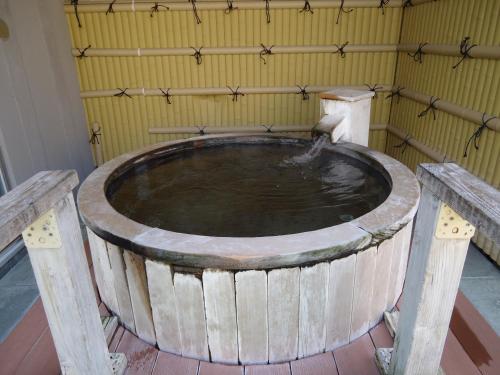 a large wooden tub in a room with a yellow wall at Yamagisi Ryokan in Fujikawaguchiko