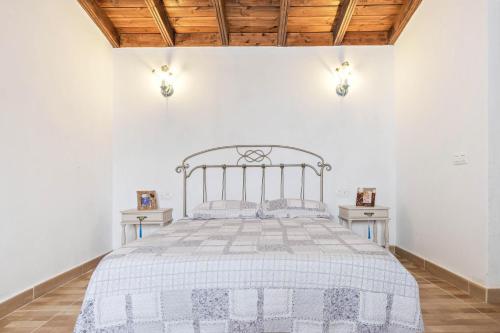 een bed in een witte kamer met 2 tafels bij Las Casas del Bisa in Garachico