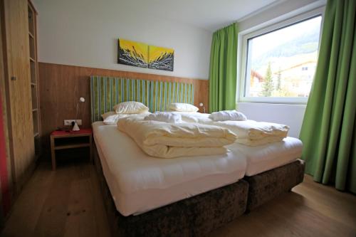 Schlafzimmer mit einem Bett mit weißer Bettwäsche und einem Fenster in der Unterkunft Rex Apart Nauders in Nauders