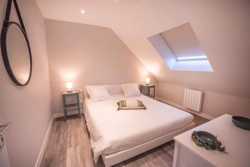 een slaapkamer met een wit bed met een tas erop bij Salicorne Villa rénovée à l'orée de la zone naturelle in Groffliers