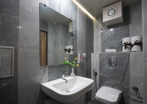 a bathroom with a sink and a toilet and a mirror at Hotel Monarch By Rivido, Bannerghatta Main Road in Bangalore