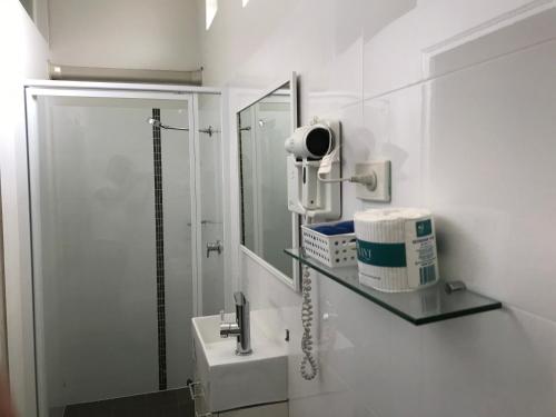 Baño blanco con lavabo y espejo en Coffs Shearwater Motel, en Coffs Harbour