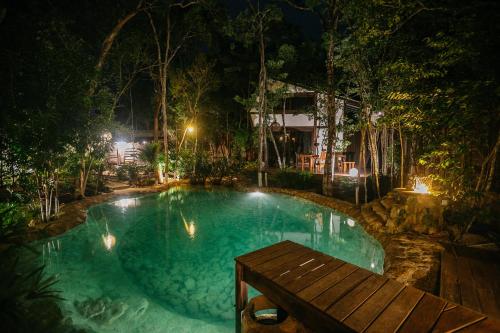 a swimming pool at night with a wooden bench at Nahouse Jungle Lodges in Tulum