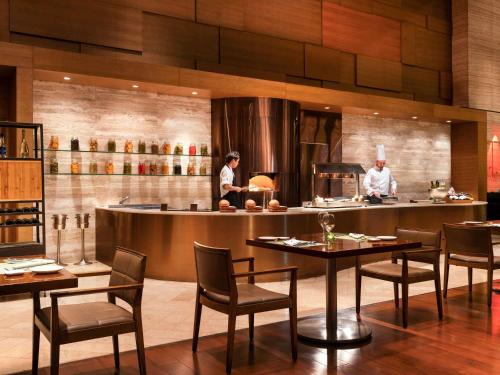two chefs preparing food in a restaurant kitchen at Novotel Citygate Hong Kong in Hong Kong
