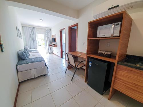 a room with a bed and a desk with a microwave at Tree Bies Resort - Oficial in Subaúma