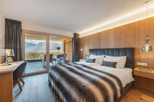 a bedroom with a bed and a desk and a balcony at Dornsberg Panoramic Apartments in Schenna