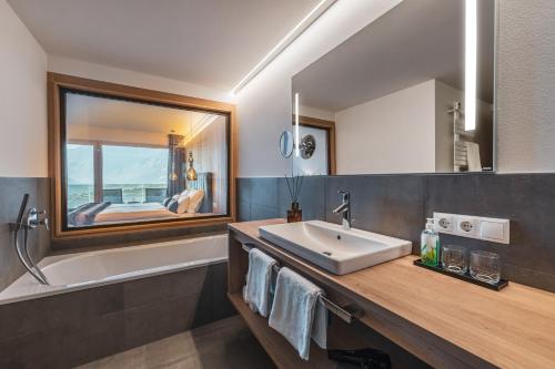 ein Badezimmer mit einem Waschbecken, einer Badewanne und einem Spiegel in der Unterkunft Dornsberg Panoramic Apartments in Schenna