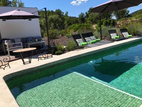 een zwembad met stoelen en een tafel en een parasol bij Villa Can Tomeu Capdet in Sant Pere de Ribes