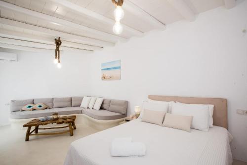 a white bedroom with a bed and a couch at Gorgeous Studio In Cycladic Architecture Overlooking The Aegean in Houlakia