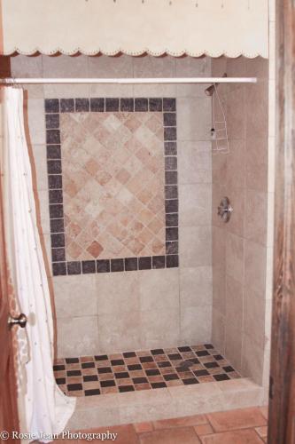 a bathroom with a shower with a tiled floor at Flowertown Bed and Breakfast in Summerville