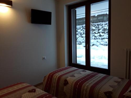 a bedroom with a bed and a window with snow outside at Apartments "STELLA ALPINA" in Santa Caterina Valfurva