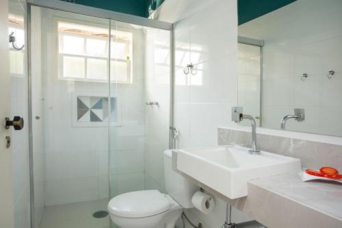 a bathroom with a toilet and a sink and a shower at Pousada Camburioca in Camburi