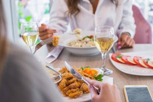 a group of people sitting at a table with food and wine at Garni Hotel Lotos in Niš