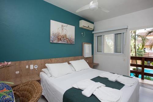 a bedroom with a white bed with a blue wall at Pousada Camburioca in Camburi
