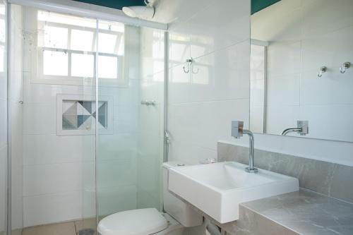 a bathroom with a toilet and a sink and a shower at Pousada Camburioca in Camburi