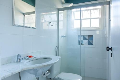a white bathroom with a sink and a shower at Pousada Camburioca in Camburi
