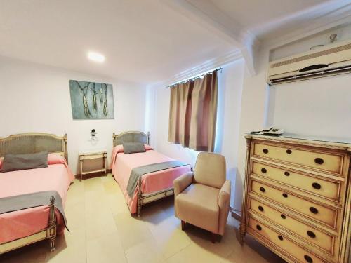 a bedroom with two beds and a dresser and a chair at Hotel Marítimo Urban in Alicante