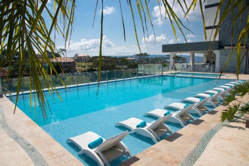 a large swimming pool with lounge chairs in front of a building at Punta Diamante Premium Hotel in Bucaramanga