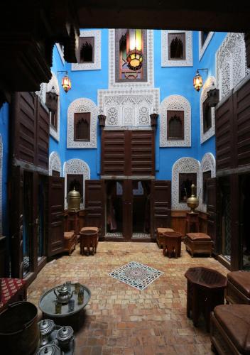a room with a blue wall with tables and chairs at Riad Hiba in Meknès