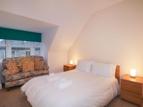 a bedroom with a large white bed and a couch at Kinnaird House in Grantown on Spey