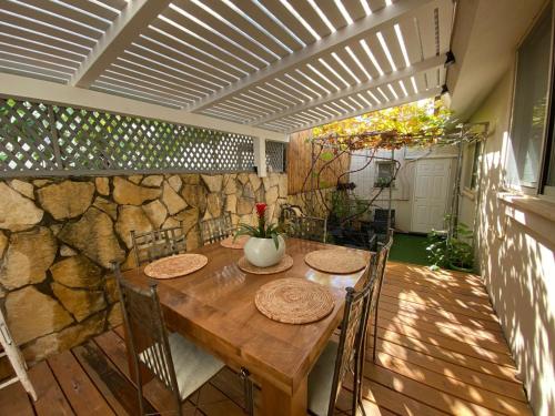 a wooden table and chairs on a patio with a stone wall at Galilee Gali in Kefar Weradim