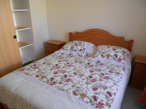 a bedroom with a bed with a floral bedspread at Cabañas Las Palmeras Pichilemu in Pichilemu