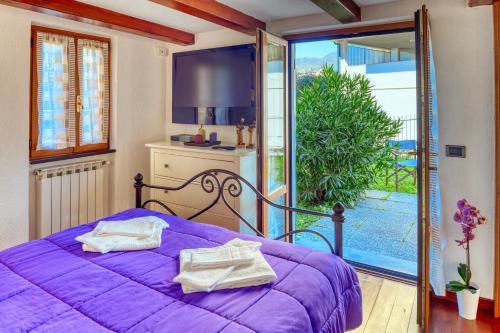 a bedroom with a purple bed and a balcony at MARIO Apartment with Garden in Levanto