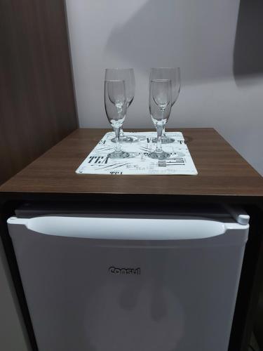 a table with two wine glasses on top of a dishwasher at Hospedagem Jardins de Gramado in Gramado