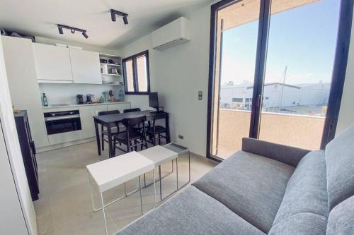 un salon avec un canapé et une cuisine avec une table dans l'établissement Modern Appartement - Les Pieds dans l'Eau - Saint-Tropez 4, à Cogolin