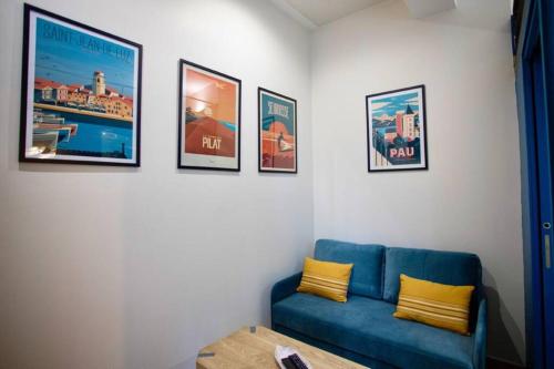 a living room with a blue couch and pictures on the wall at Tiny House in Pau